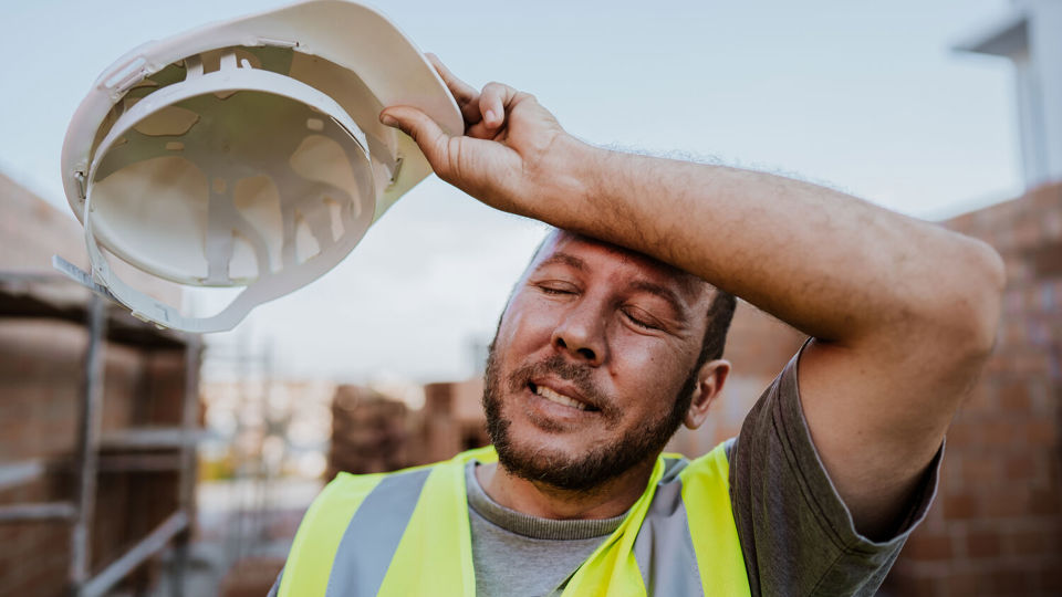 Construction worker remving hardhat in the sun