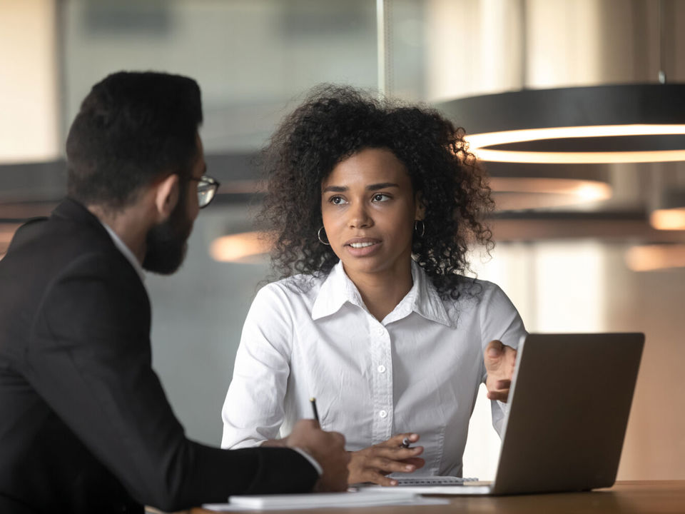 Man and woman talking whilst looking at laptop computer