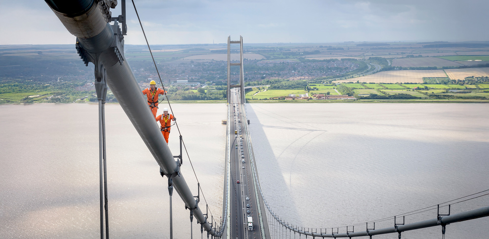 Two men in hi-vis clothing working at height on a bridge