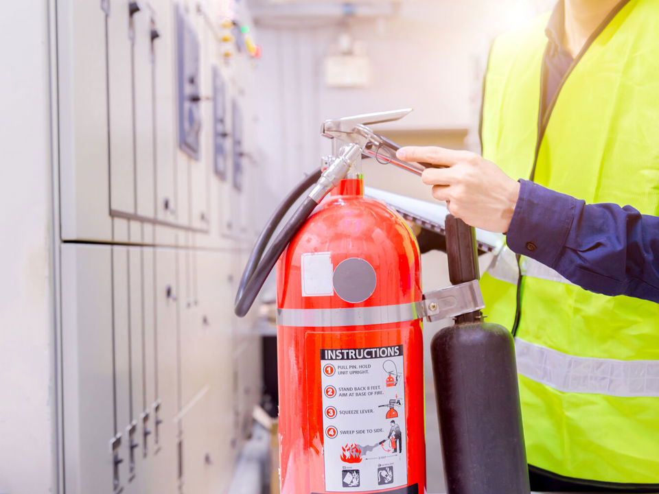 Person in high-vis jacket holding fire extinguisher