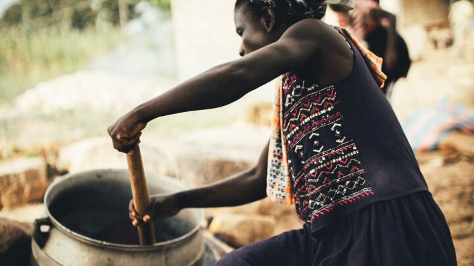 A shea butter farmer in Ghana stirs the mush in a pot