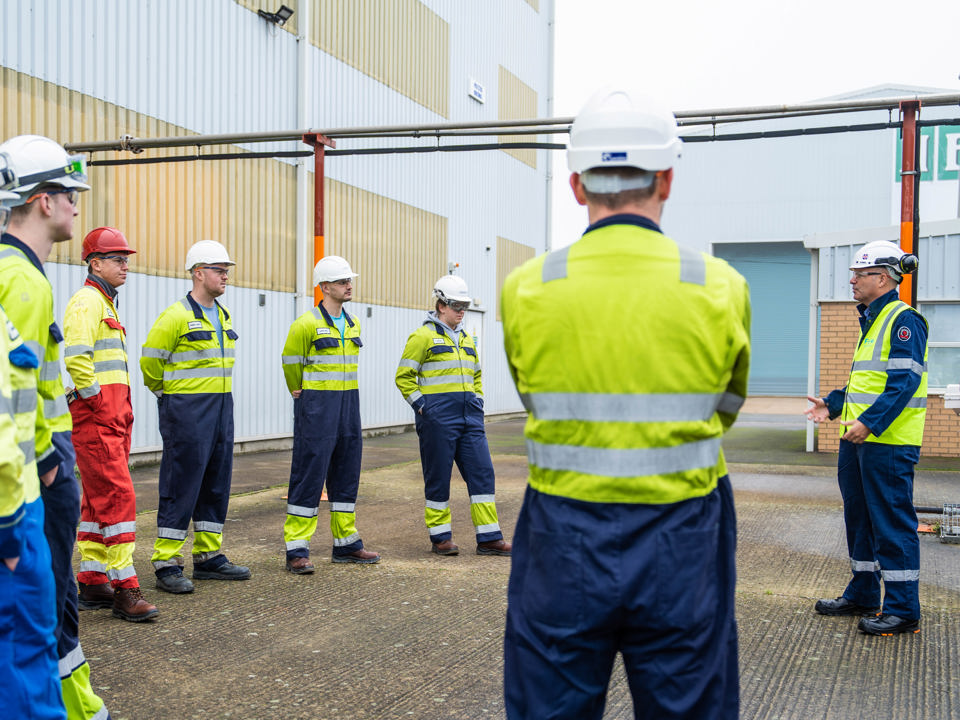 People in hard hats and high vis vests standing in a circle