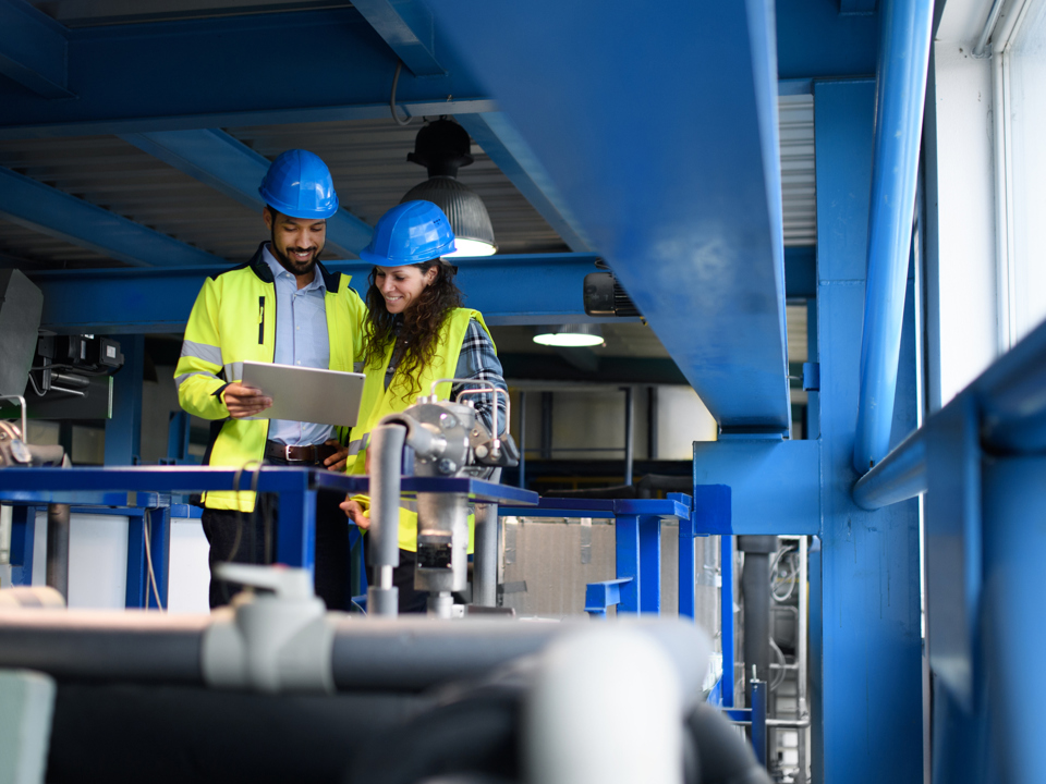 Male and female factory workers looking at tablet computer