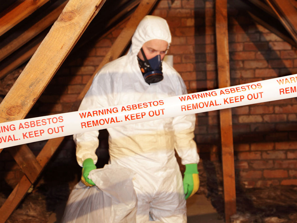 Hand placing asbestos warning label